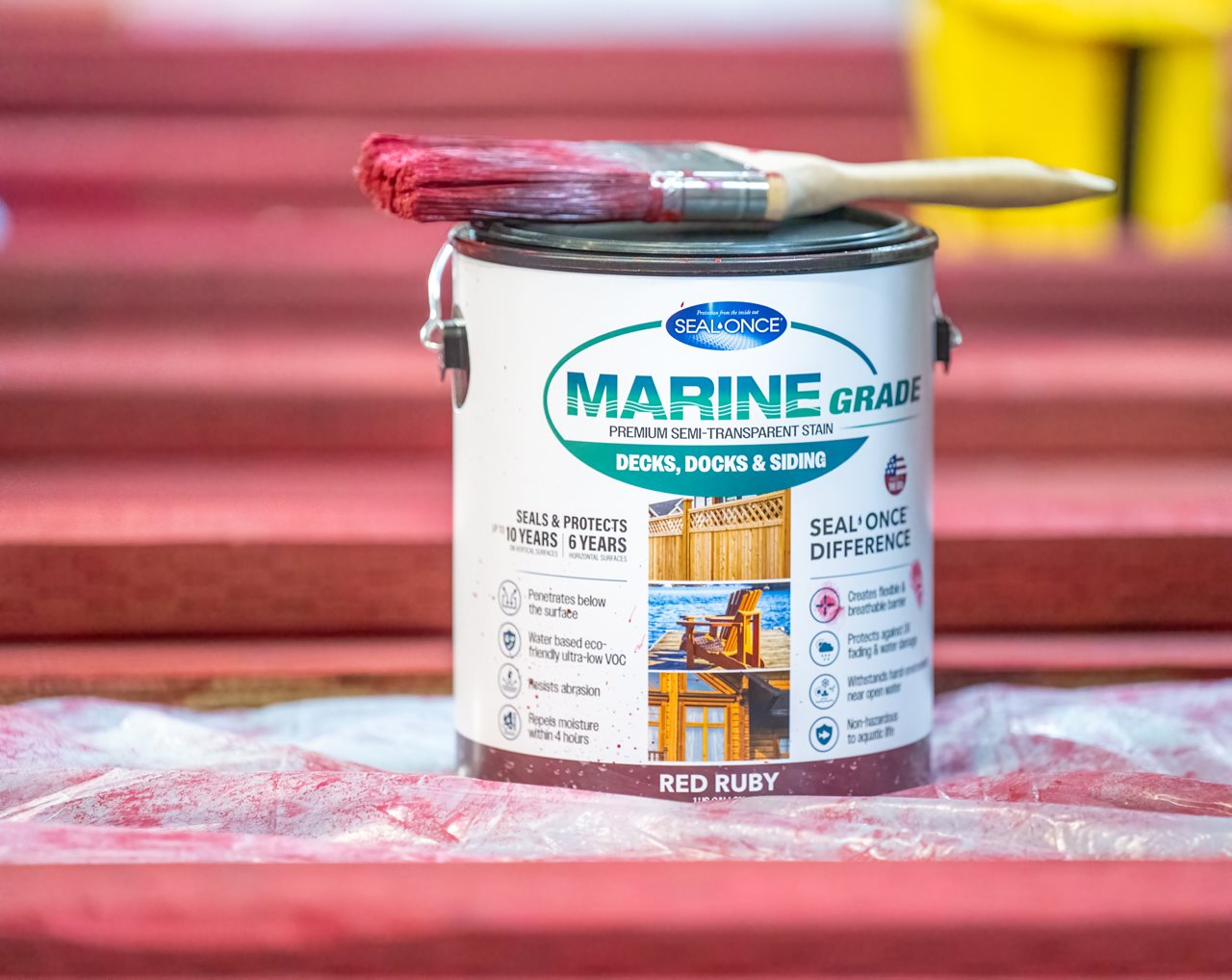 Close up of a can of red Marine grade paint with a paint brush layed accross the top.